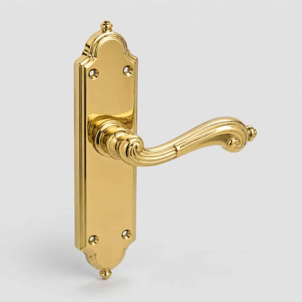 Poignée de porte ancienne en laiton poli doré de forme travaillée